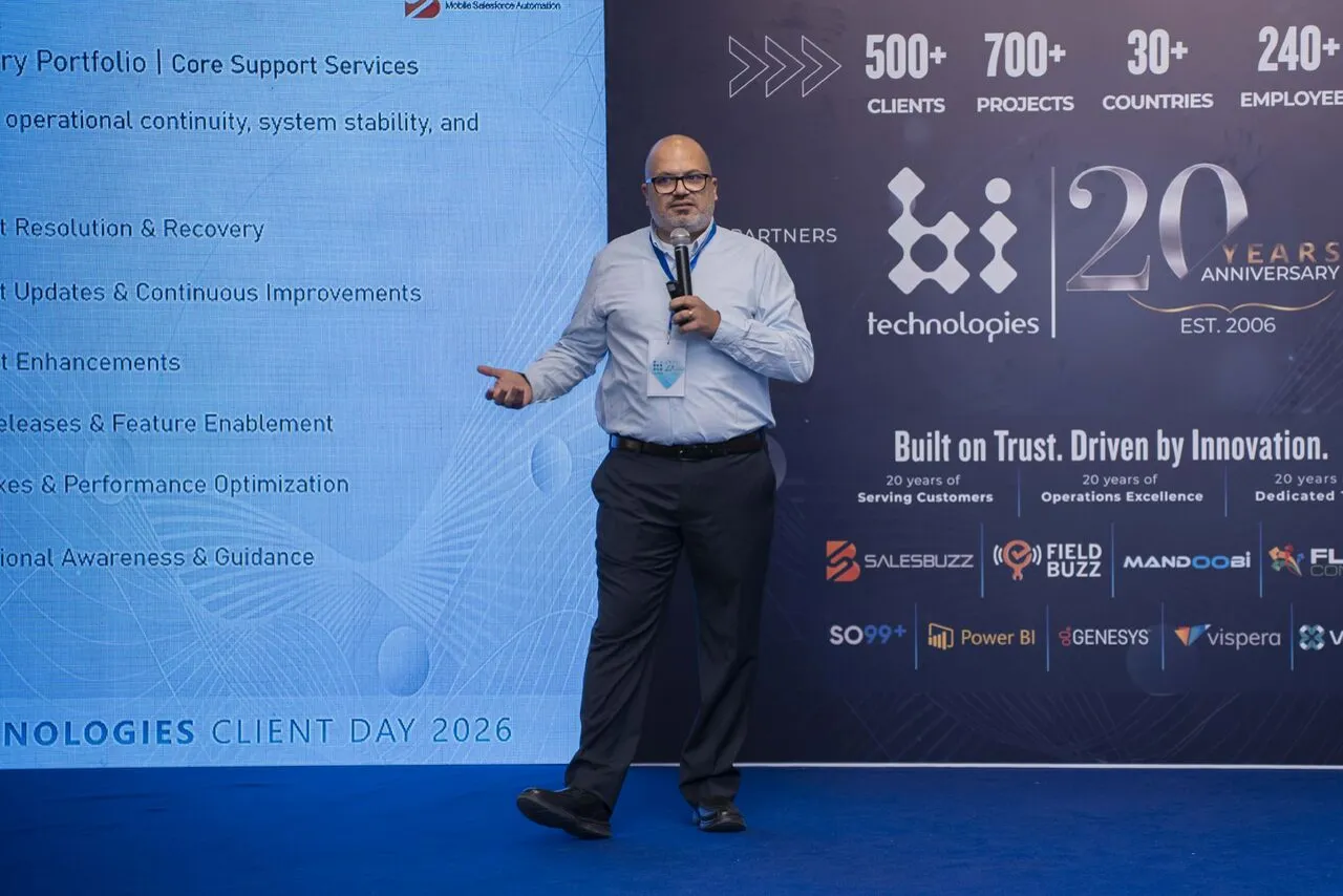 Peter GORGY presenting Core Support Services on stage at BI-Technologies Client Day 2026, in front of the 20 Years Anniversary backdrop