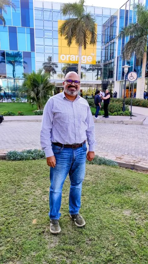 Peter GORGY standing on the lawn in front of an Orange Egypt office building.