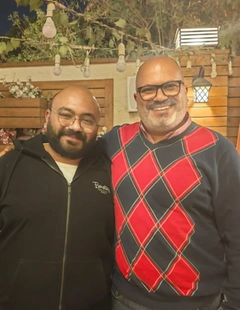 Peter GORGY and Mina El-Raheb smiling together outdoors under string lights
