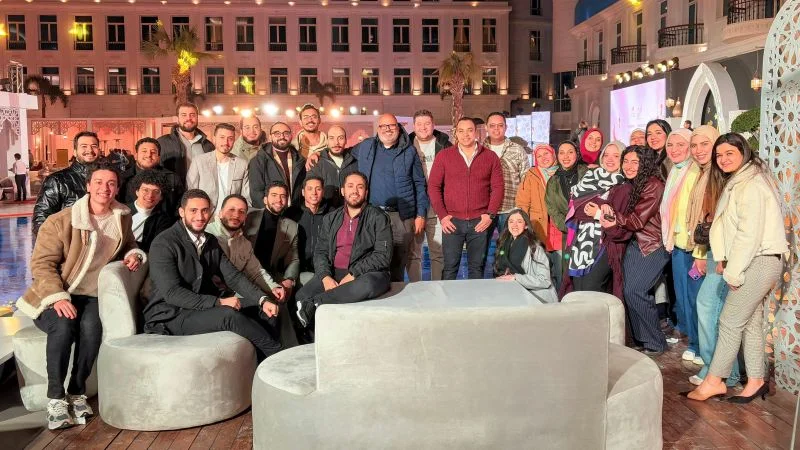Peter GORGY with a large group of his Service Delivery team at an evening Iftar gathering, standing and seated around white lounge sofas